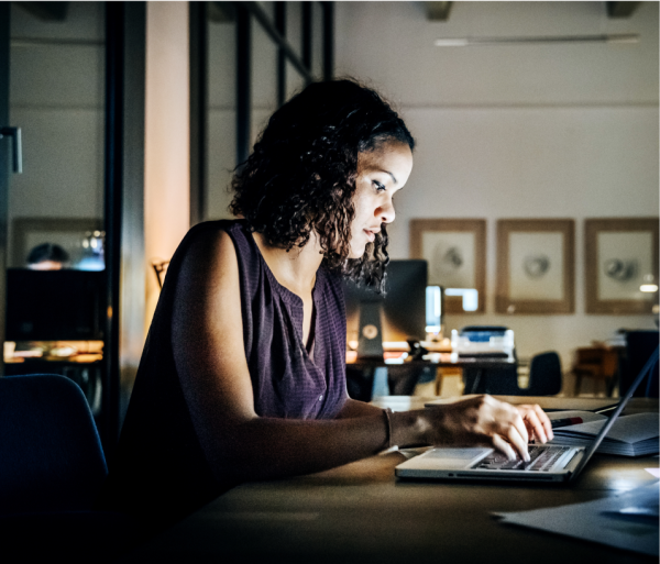 Woman in an office seated at a desk working on a laptop