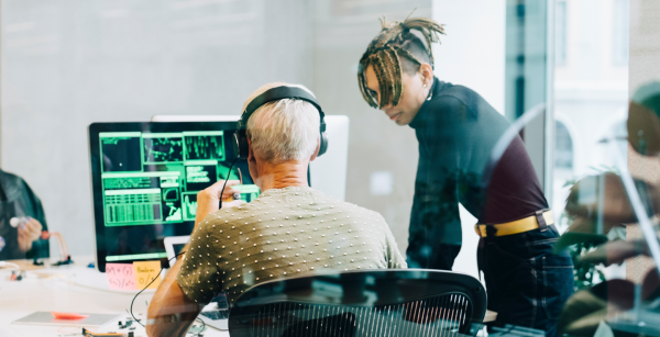 Colleagues gather to discuss technology issues around a computer screen