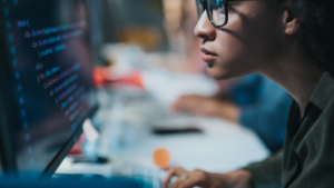 Individual sitting at a desk coding on their computer